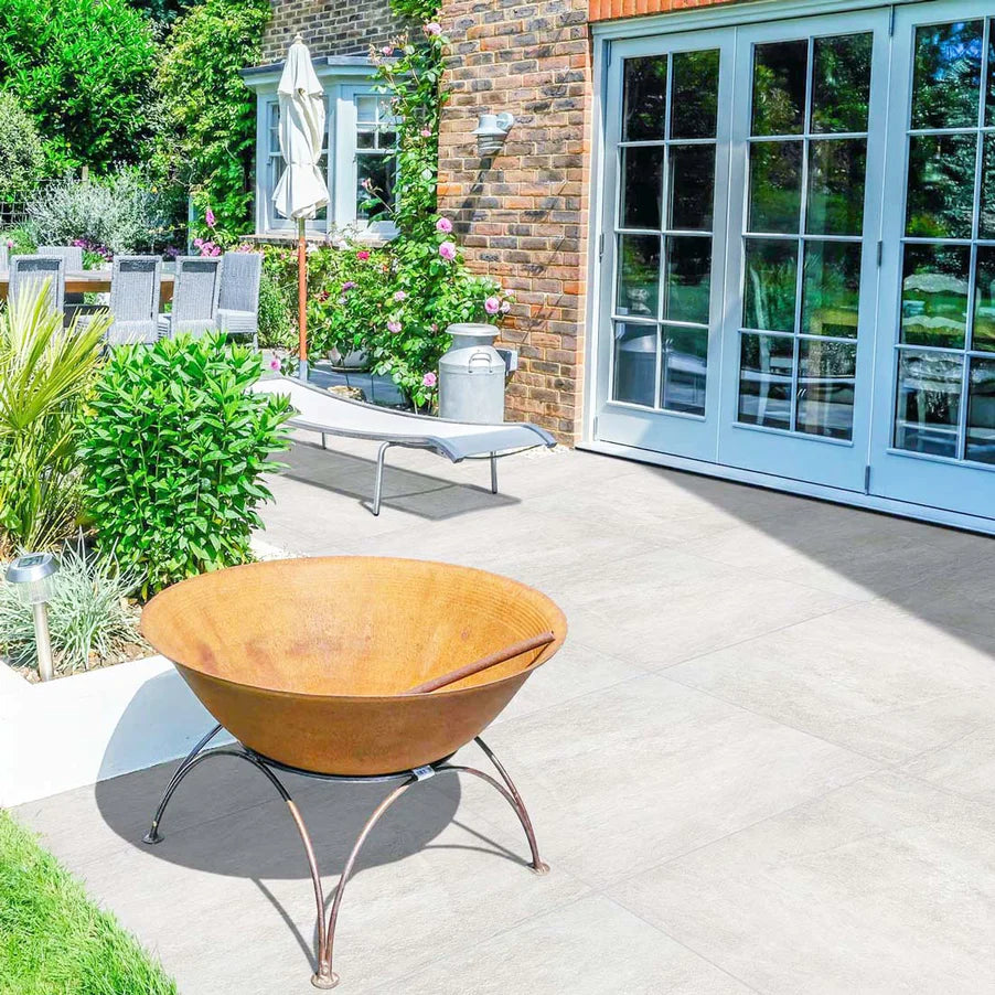 Lisbon White Outdoor Porcelain tiles 60x60cm patio with fire pit, lounger and greenery outside french doors.