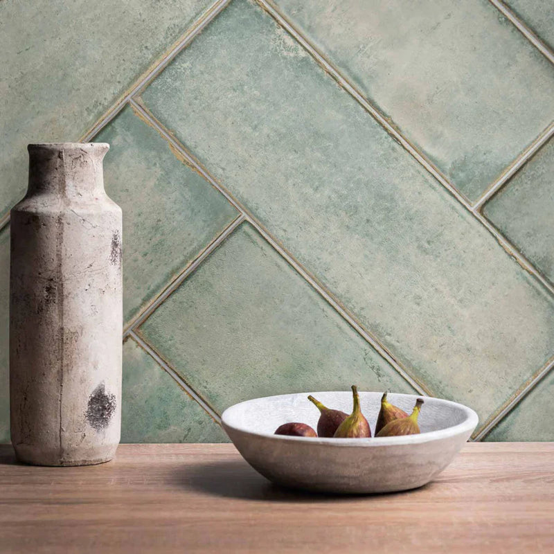 Image of   Click to expand Montblanc Sage Tile Original Style Tileworks in a herringbone pattern. Wooden table with pears in a white bowl and grey bottle. 