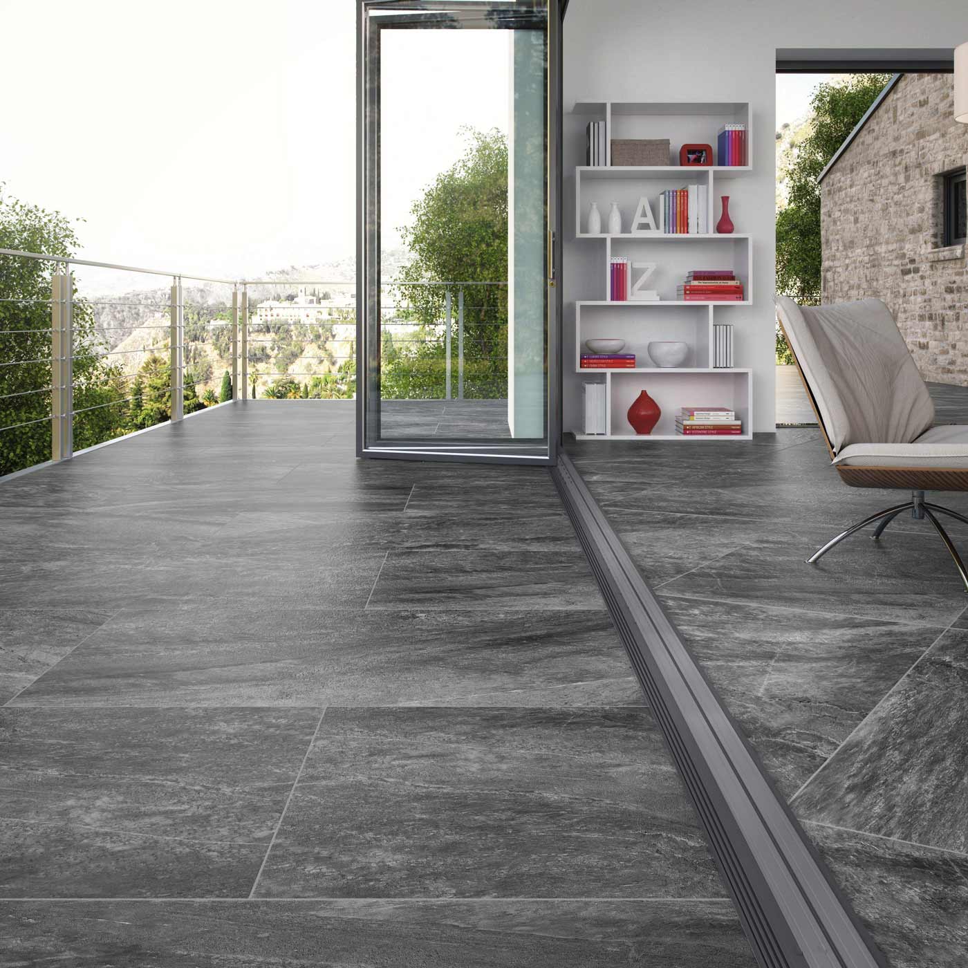 Outdoor Porcelain tile 60x90cm Everest Anthracite in a lounge and terrace setting. bi-fold doors open the lounge to the terrace. Bookcases line the walls with a white sofa in the lounge