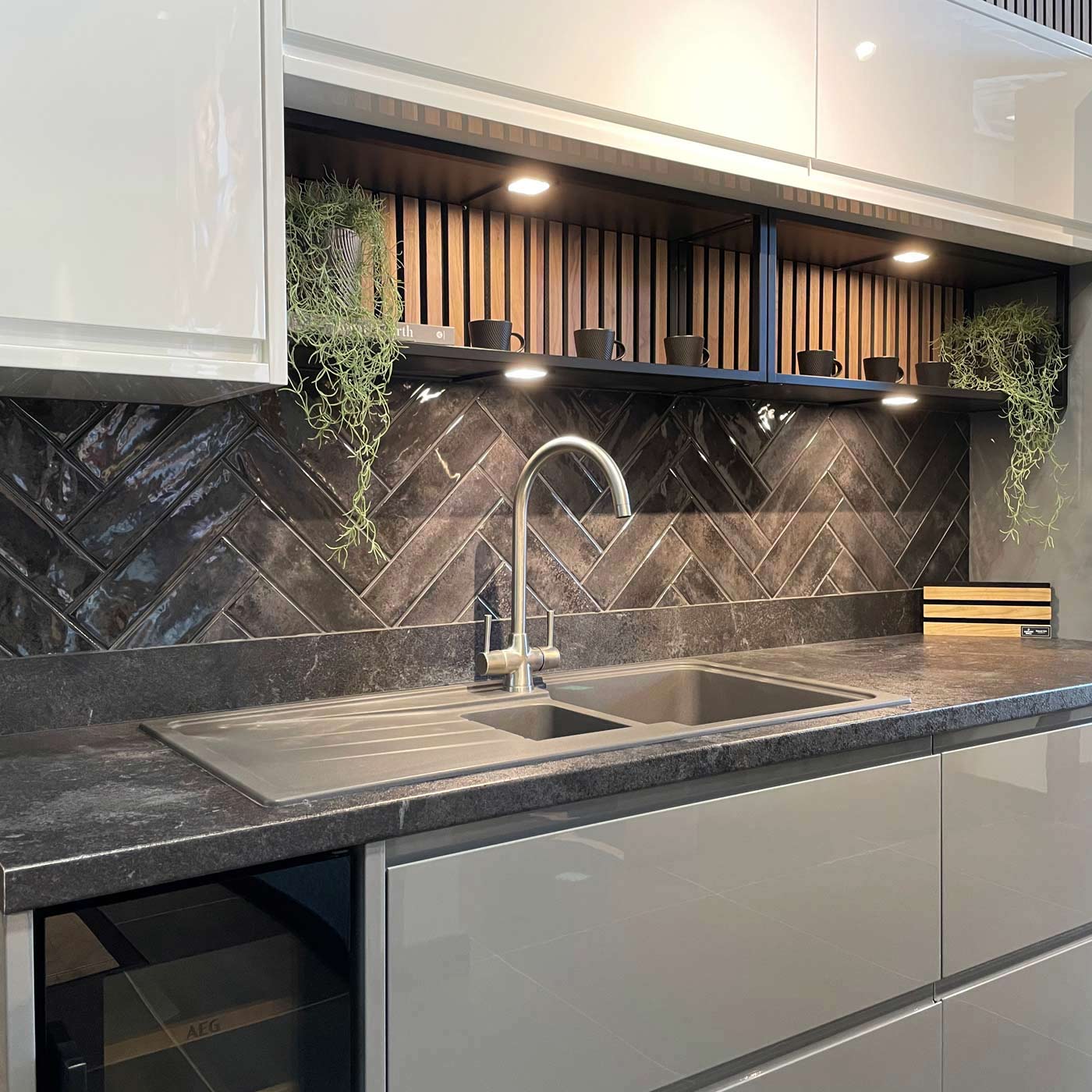 nissel black wall tile as a kitchen splash back with white kitchen units and sink tap