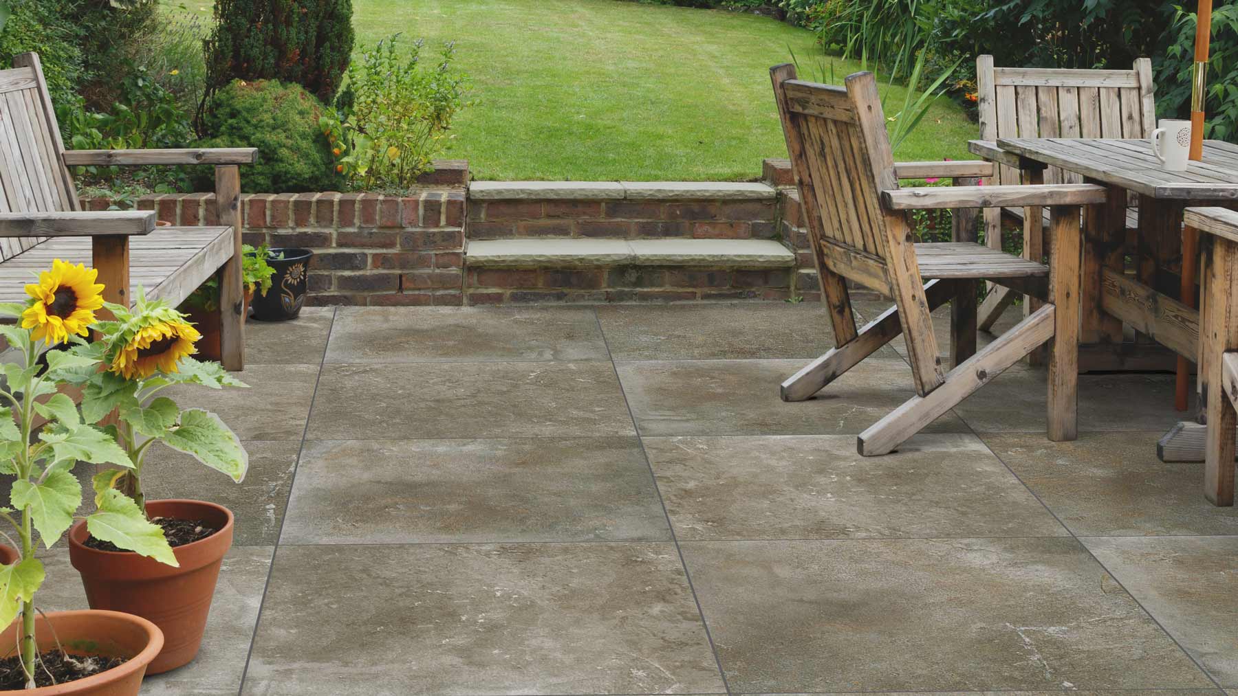 Image of porcelain outdoor tiles with grass, sunflowers and wooden furntiure