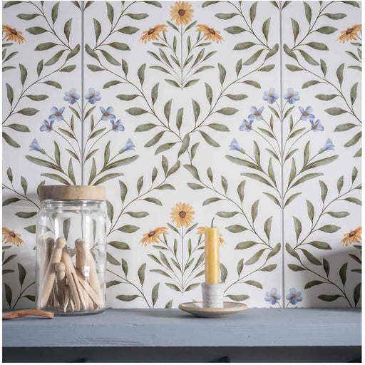Floral tile backsplash with a jar of wooden pegs and a small candle on a blue shelf.