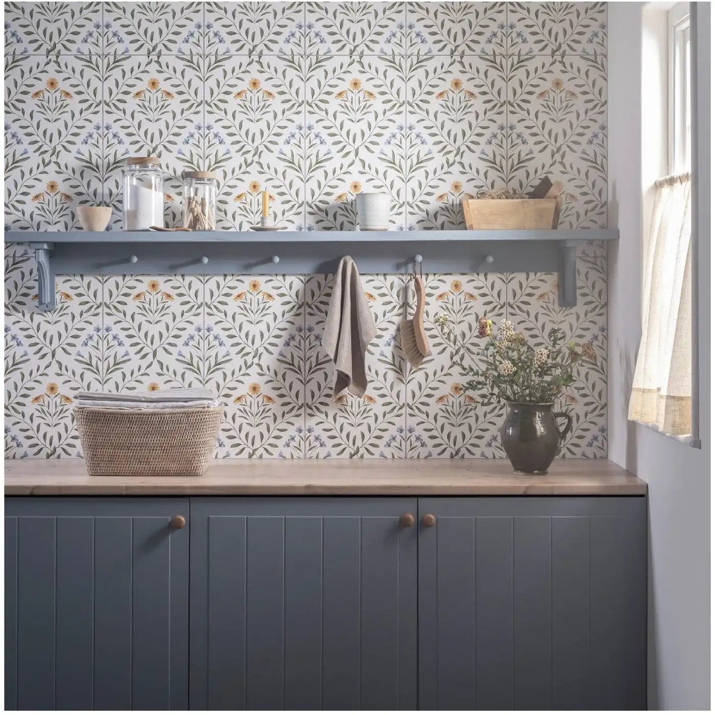 Image of Patterned floral tile backsplash with a shelf, kitchen accessories, and cabinets below.