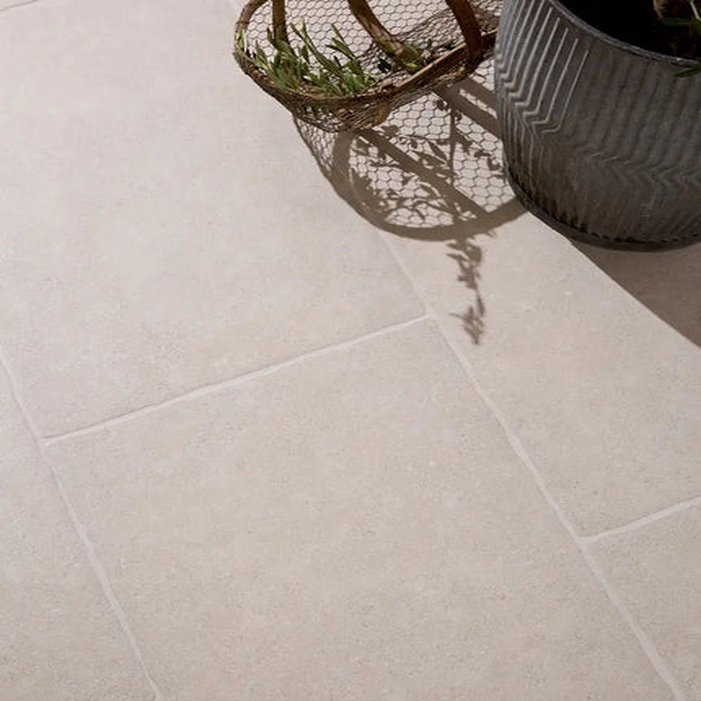 Image of Close-up of a tiled floor with two plant pots casting shadows.