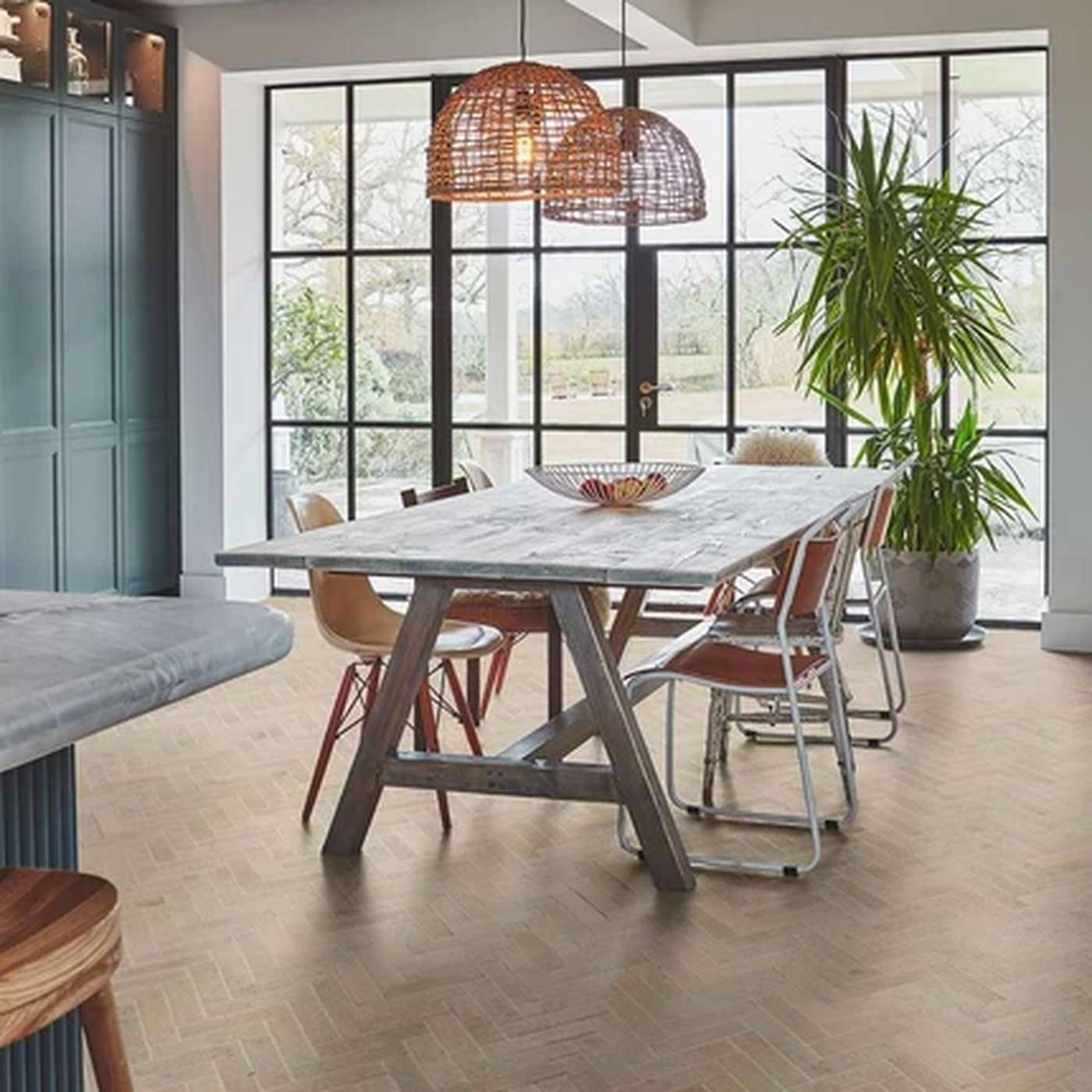 Image of A dining room scene with a rectangular table and chairs, large black-framed windows, pendant lights, a potted plant, and a light wood floor.