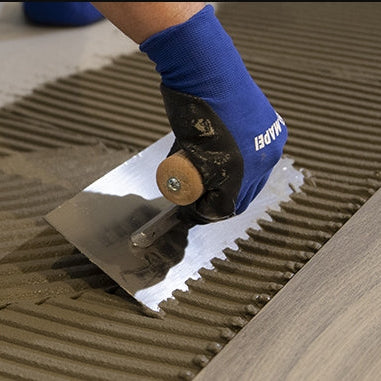 Image of Person applying adhesive to a tile with a trowel
