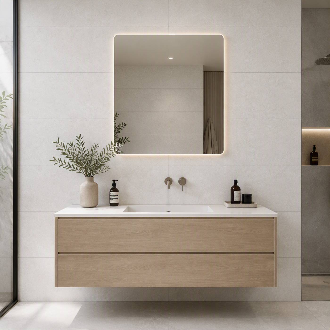 Image of Modern floating bathroom vanity with a white sink, light wood cabinet, wall-mounted mirror with LED lighting, and minimalist toiletries in a bright tiled bathroom.