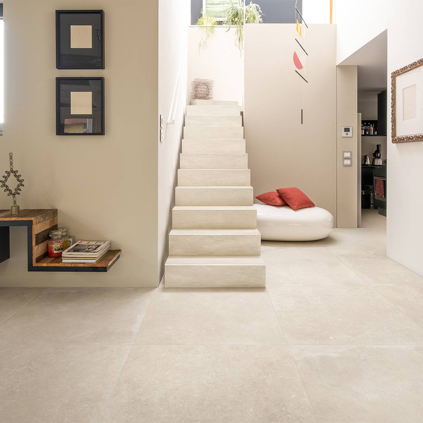 Image of A modern interior space featuring large, light beige stone-look floor tiles that blend seamlessly with the minimalist concrete staircase and cream-colored walls.