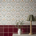 Floral wall tiles with a red border, a jug of greenery, and a wooden lamp.