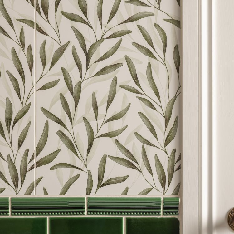 Image of Leaf-patterned wall tiles with a green tiled border, a wooden bench, and a wicker umbrella stand.