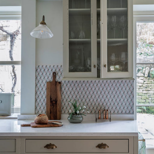 Kitchen interior with a white cabinet, countertop, and decorative backsplash.