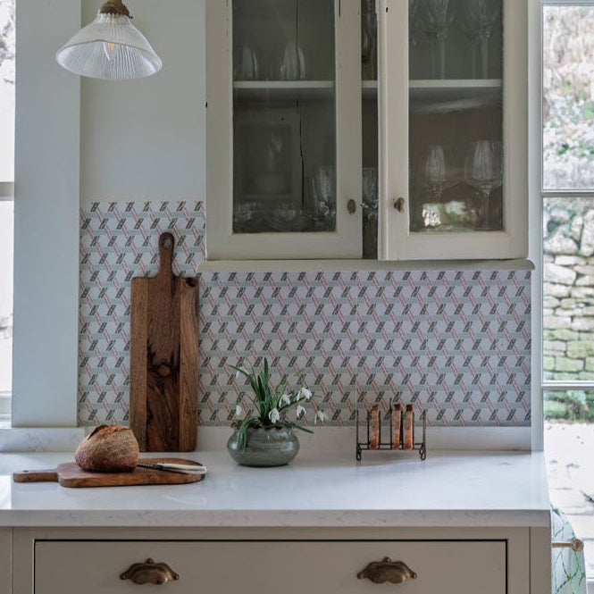 Kitchen interior with a white cabinet, countertop, and decorative backsplash.