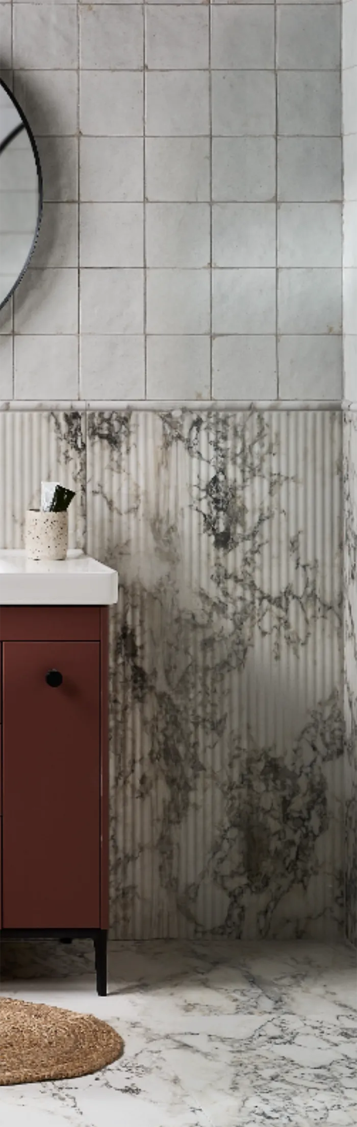 Modern bathroom with a round mirror, sink, and decorative tiles that look like marble.