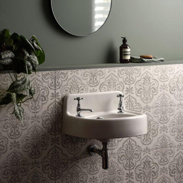 Bathroom with a wall-mounted sink, decorative tiles, and a plant.