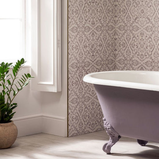 White freestanding bathtub in a bathroom with patterned wallpaper and a plant.
