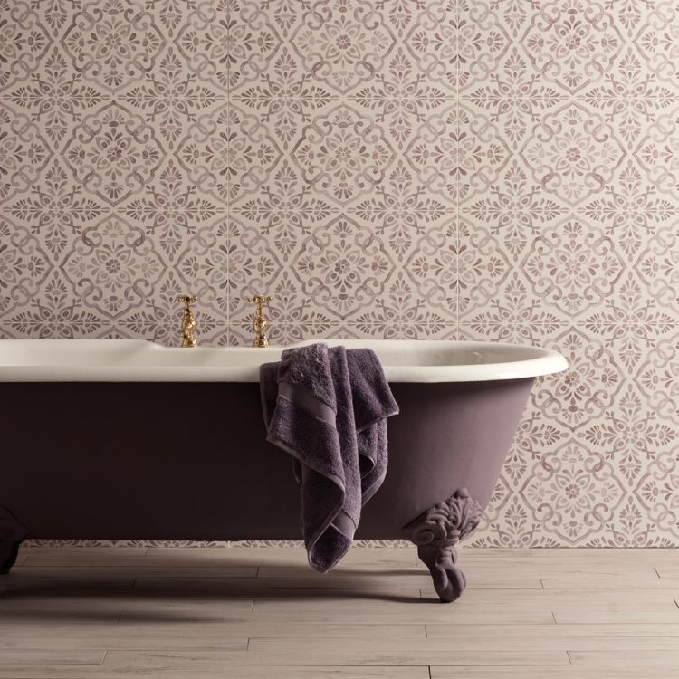 Image of Purple freestanding bathtub with a towel against a patterned wallpaper wall.
