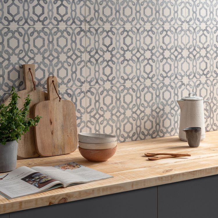 Image of Kitchen counter with wooden cutting boards, bowls, and a plant against a patterned tile wall.