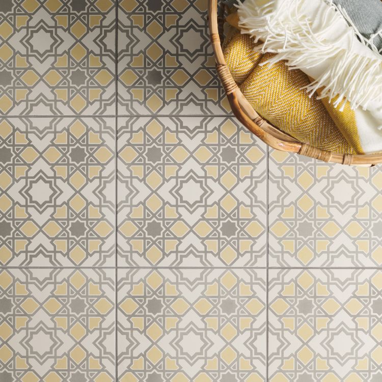 Image of Patterned floor tiles in yellow and grey with a geometric design, shown beside a woven basket filled with folded blankets.