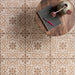 Decorative tiles with geometric pattern on a floor, featuring a notebook and pen on a wooden stool.