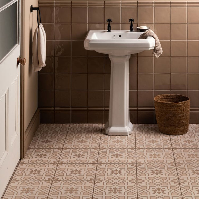 Bathroom with a white pedestal sink against a tiled wall.