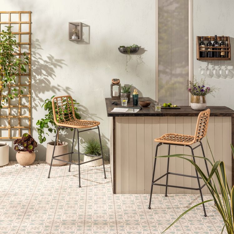 Image of Outdoor patio area with a wooden bar and wicker chairs, featuring plants and a decorative wall shelf.