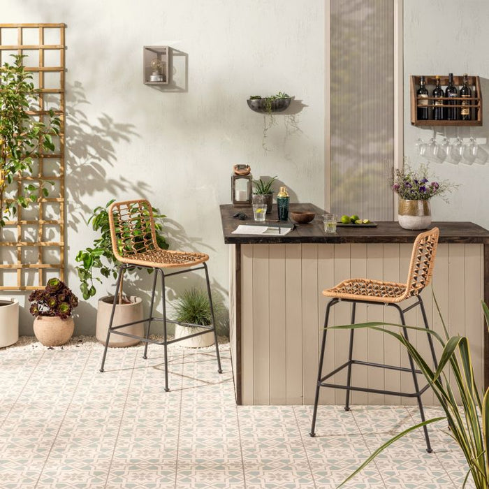 Outdoor patio area with a wooden bar and wicker chairs, featuring plants and a decorative wall shelf.
