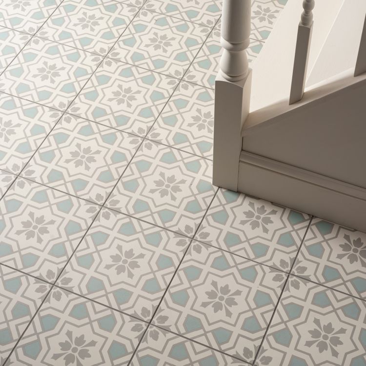 Image of Patterned tiles on a floor with a chair leg visible