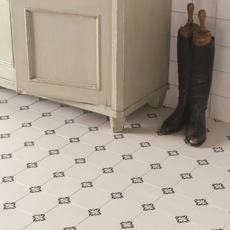 Image of Black and white patterned tile floor with a wooden cabinet and black boots.