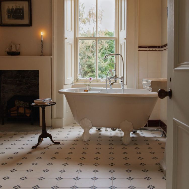 Image of Bathroom with a freestanding bathtub near a large window, featuring a fireplace and decorative elements.