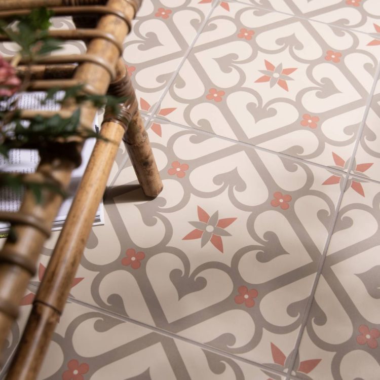 Image of Patterned floor tiles in taupe and rose tones beside a woven bench, with part of a magazine visible underneath