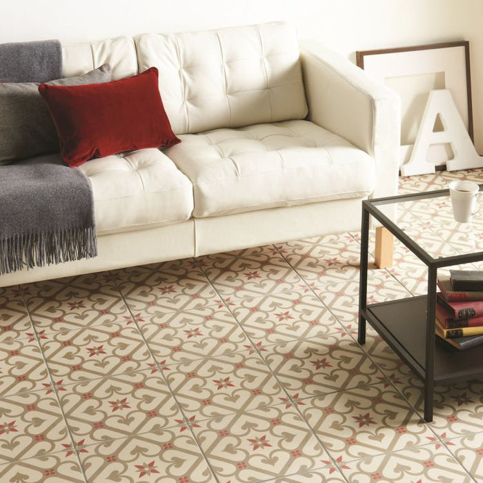 Living room with patterned floor tiles in taupe and rose tones, featuring a cream sofa with cushions and a blanket, and a black metal coffee table