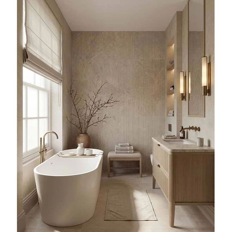 Image of A modern bathroom interior with a freestanding white bathtub near a window, a light wood vanity with a white sink, beige textured walls, wall-mounted mirrors, and gold-toned wall sconces.