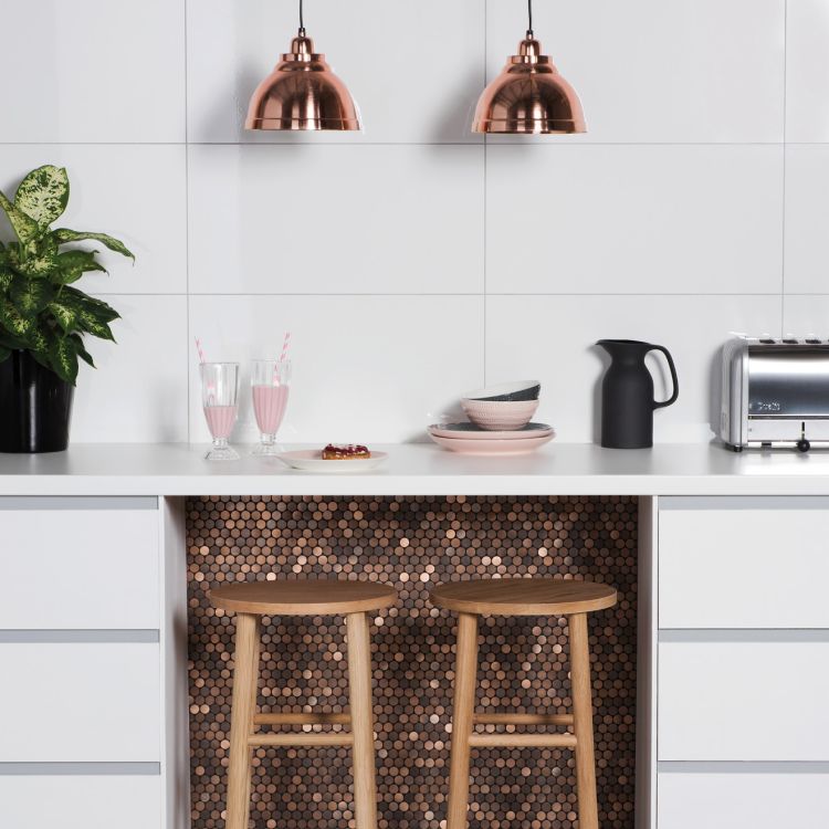 Image of Modern kitchen with white cabinets, copper pendant lights, wooden stools, and a copper penny‑round tile feature beneath the counter.