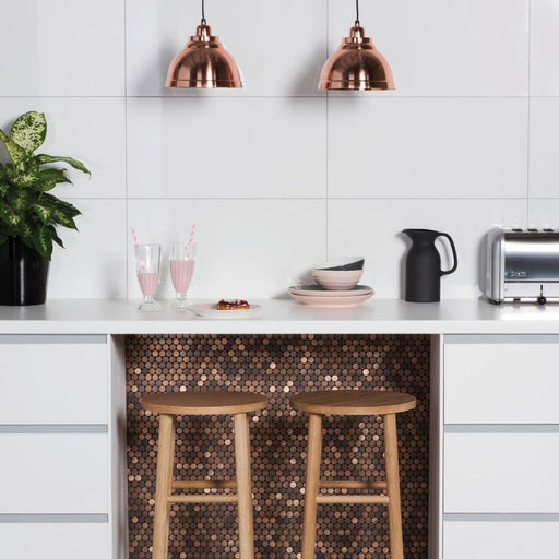 Modern kitchen with white cabinets, copper pendant lights, wooden stools, and a copper penny‑round tile feature beneath the counter.
