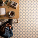 Person sitting at a table with a cup of coffee, surrounded by patterned tiles.