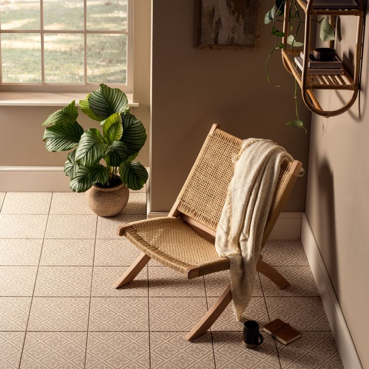 Image of Wicker chair with a towel draped over it in a sunlit room with plants and a window.
