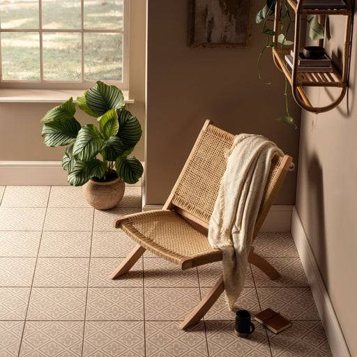 Wicker chair with a towel draped over it in a sunlit room with plants and a window.
