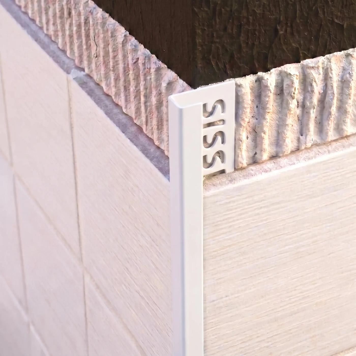 Image of Close-up of a matt white square edge tile trim fitted to an external corner of cream ceramic wall tiles.