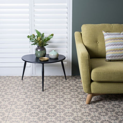 Green sofa with a decorative pillow in a room with a black side table and plant.