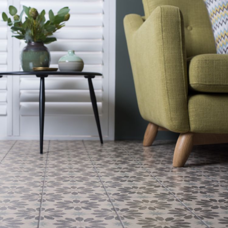 Image of Green armchair in a room with patterned floor tiles and a small table with decorative items.