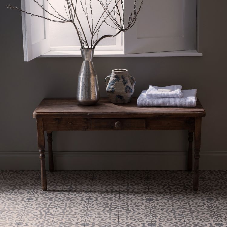 Image of Wooden table with decorative items including a vase and folded towels against a dark wall.