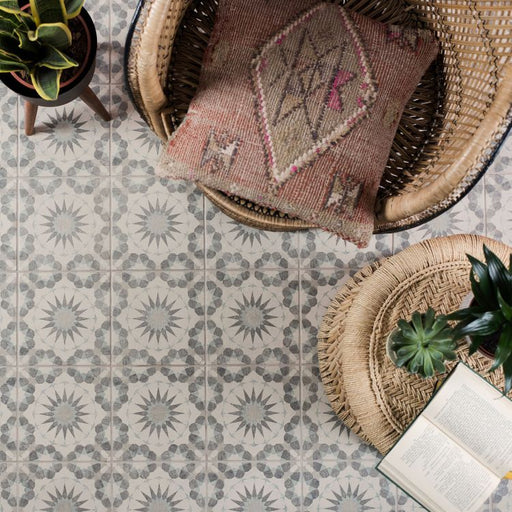 Decorative patterned tiles with a woven basket, plant, and book on a floor.