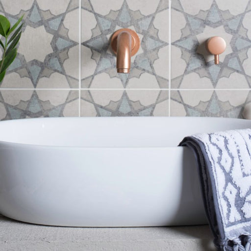 Bathroom setting with a white bathtub, decorative tiles, and a towel.