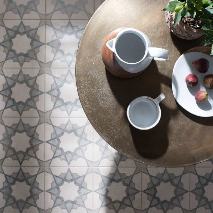 Image of Round wooden table with ceramic pitcher and cups on a patterned tile floor