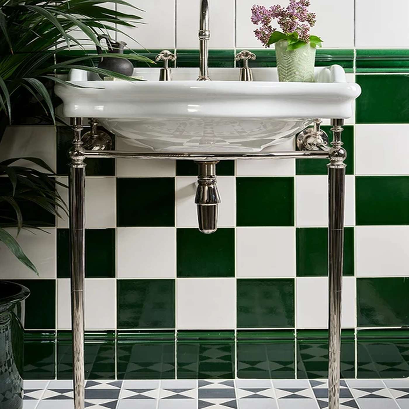 Image of White sink with silver faucet against a green and white tiled wall
