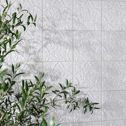 wall tiled with small white square patterned tiles, green plant over the tiles 