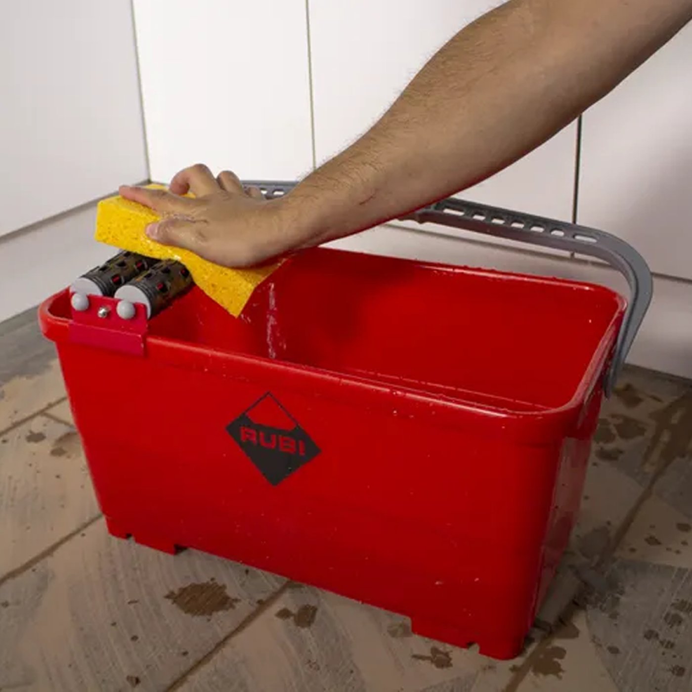 Image of Person cleaning a surface with a red bucket and sponge, Rubi logo visible