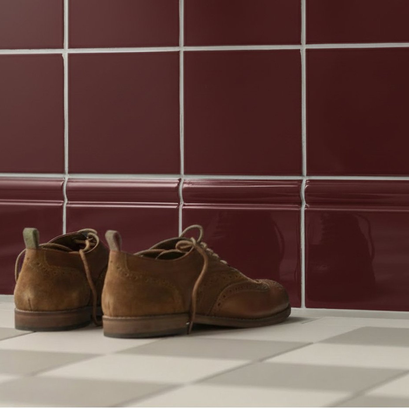 Image of Brown suede shoes on a checkered floor with red tiled wall