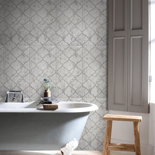 Bathroom with white bathtub, patterned tiles, and wooden stool.