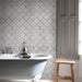Bathroom with white bathtub, patterned tiles, and wooden stool.